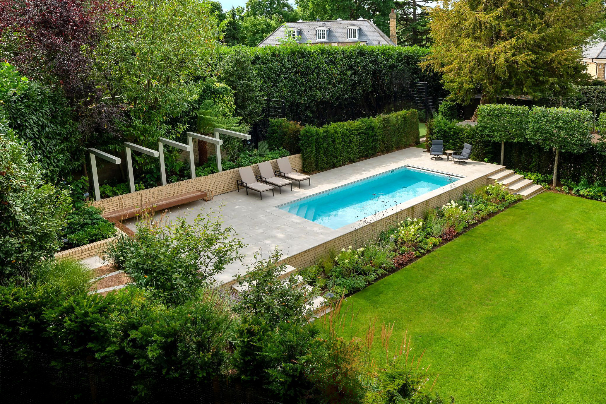 Contemportary swimming pool and pergola in garden setting.